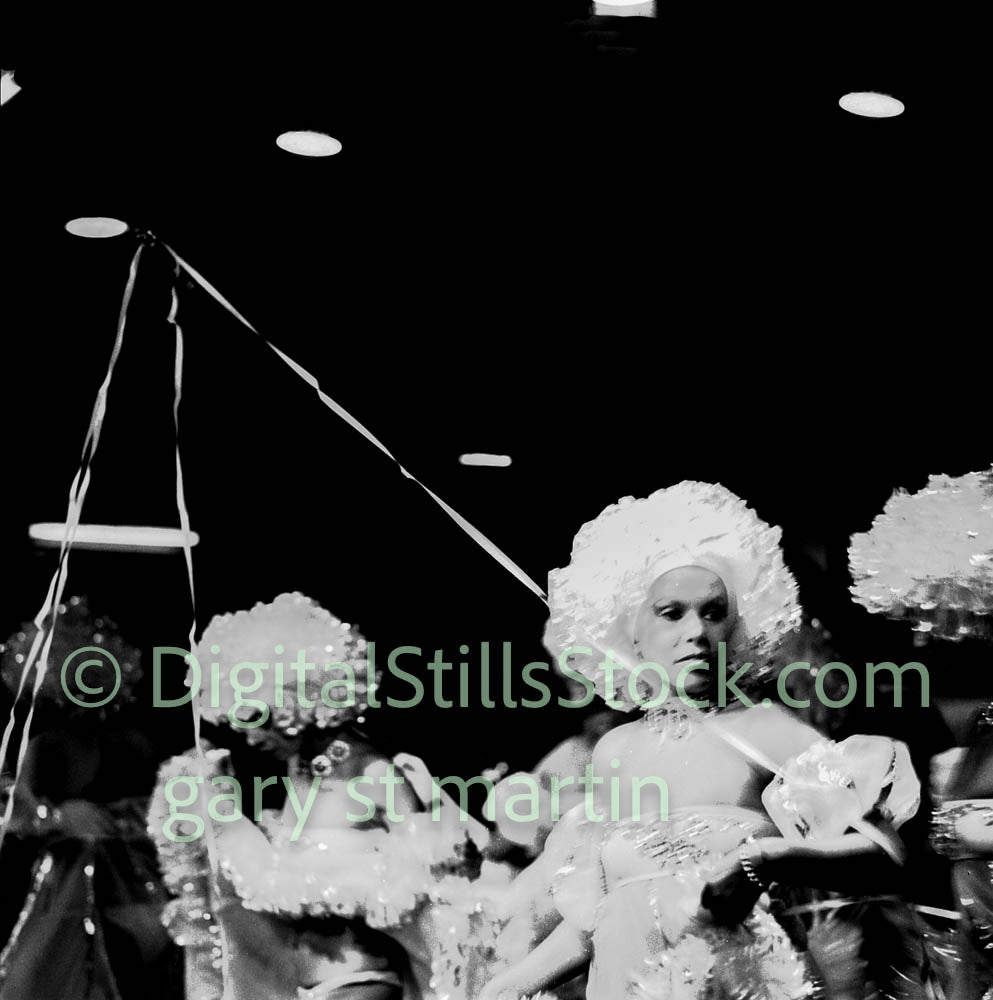 Black and white photo of performers in elaborate costumes with headpieces.