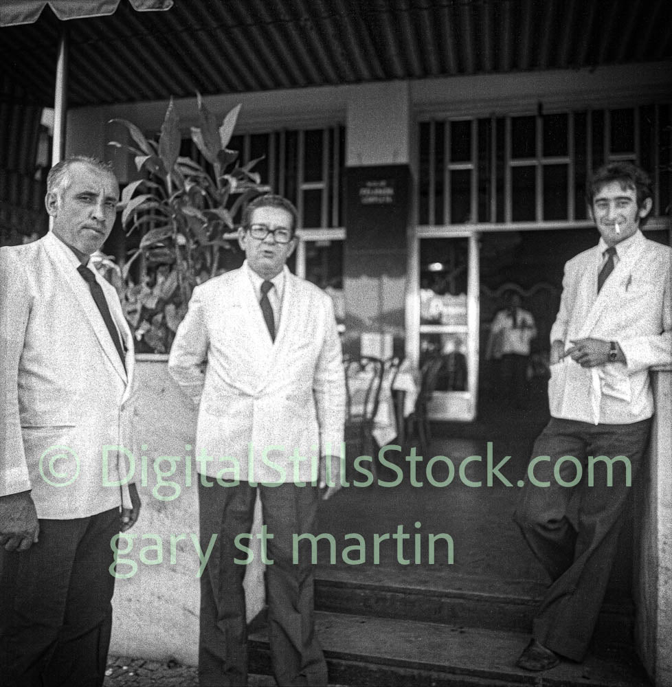 Three men standing outside a building with a sign in the background