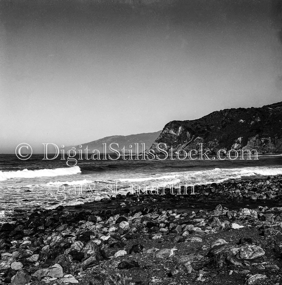 Distant Mounds Across Rocky Beach in California