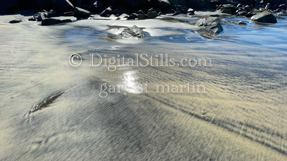 Jagged rocks in the shiny sand, digital sunset