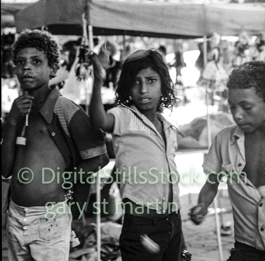 Black and white photograph of three children at an outdoor event with a tent in the background.