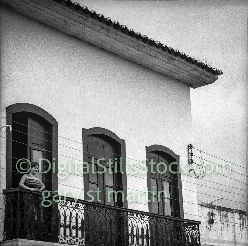 Black and white photo of a building with a balcony and window.
