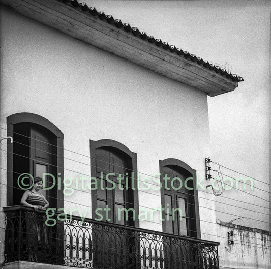 Black and white photo of a building with a balcony and window.
