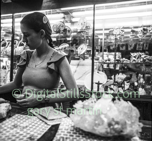 Woman working in a store with shelves and crystal products in the background
