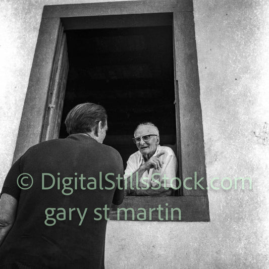 Two men interacting through a small window in a building.