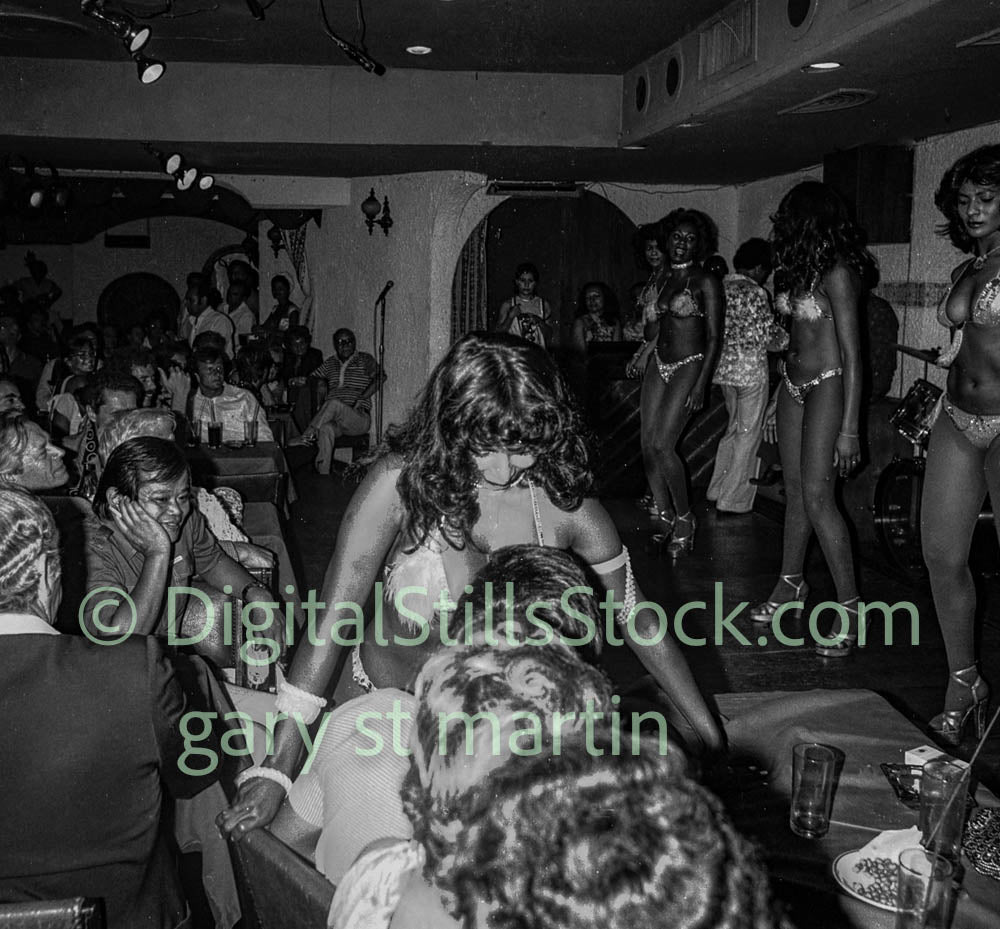 Black and white scene of a lively indoor event with people and performers.