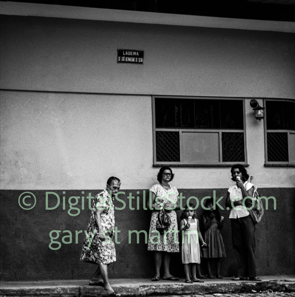 Black and white photograph of a group of women and children standing against a building.
