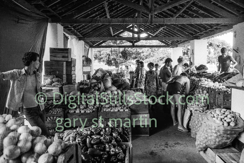 Black and white photograph of a market scene with people and produce.