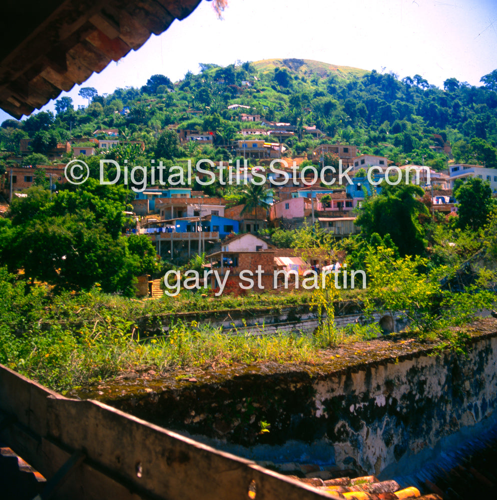 Hillside village with houses and greenery, taken from a high vantage point.