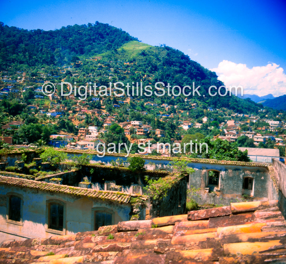 Ruins of an old building with a scenic background of green hills and blue sky.