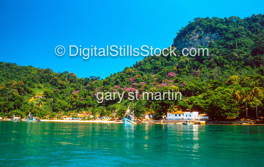 Lagoon with boats and lush green mountains under a clear blue sky