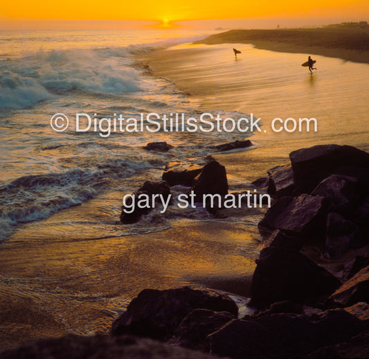 Surfers rushing into the crashing waves, analog sunset
