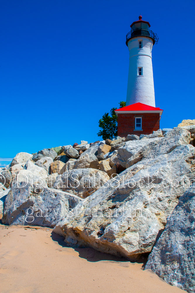 Close up of rocks on the beach with lighthouse in the background, digital Crisp Point